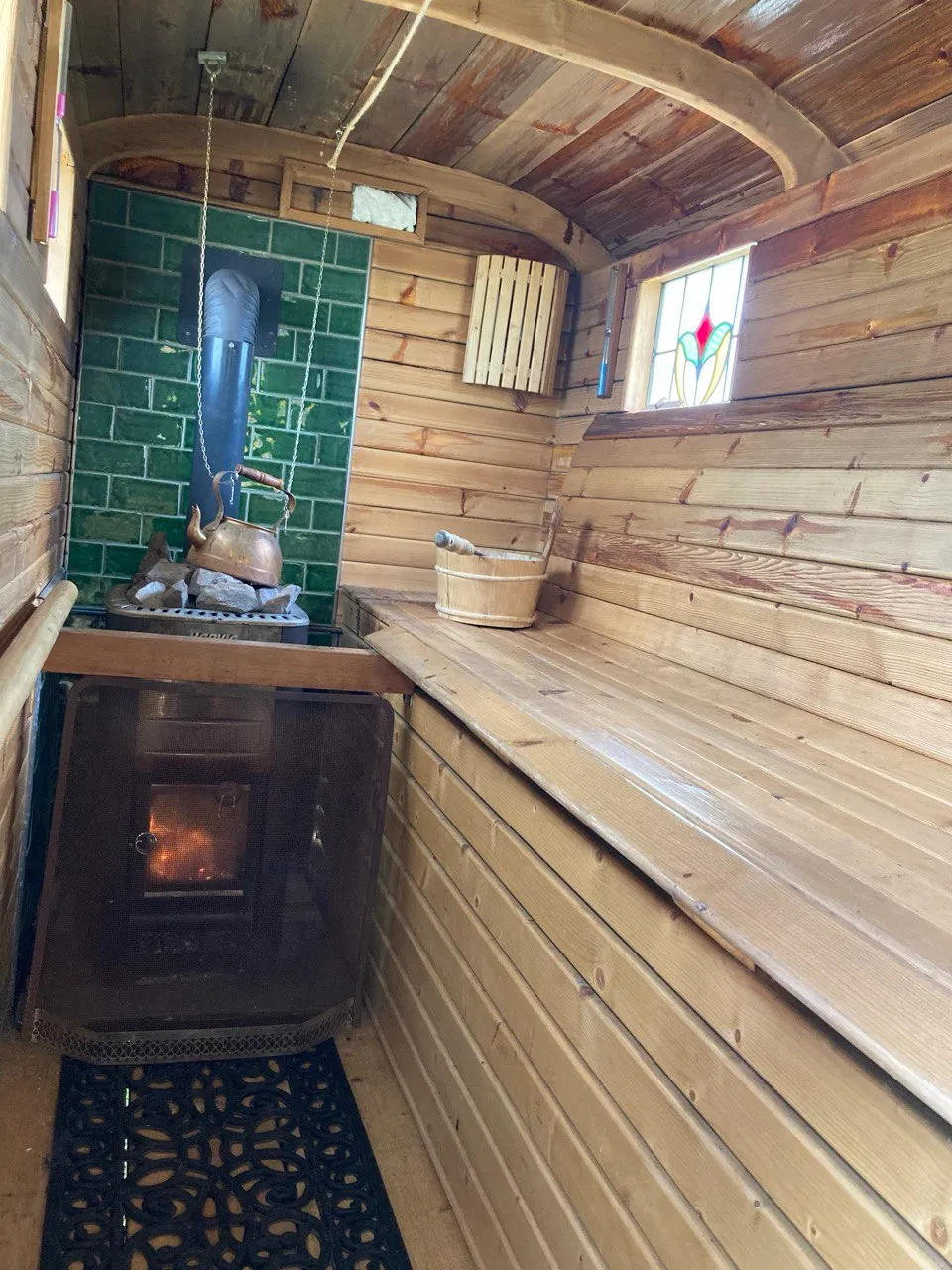 The wood-burning stove glowing inside the pine-panelled sauna