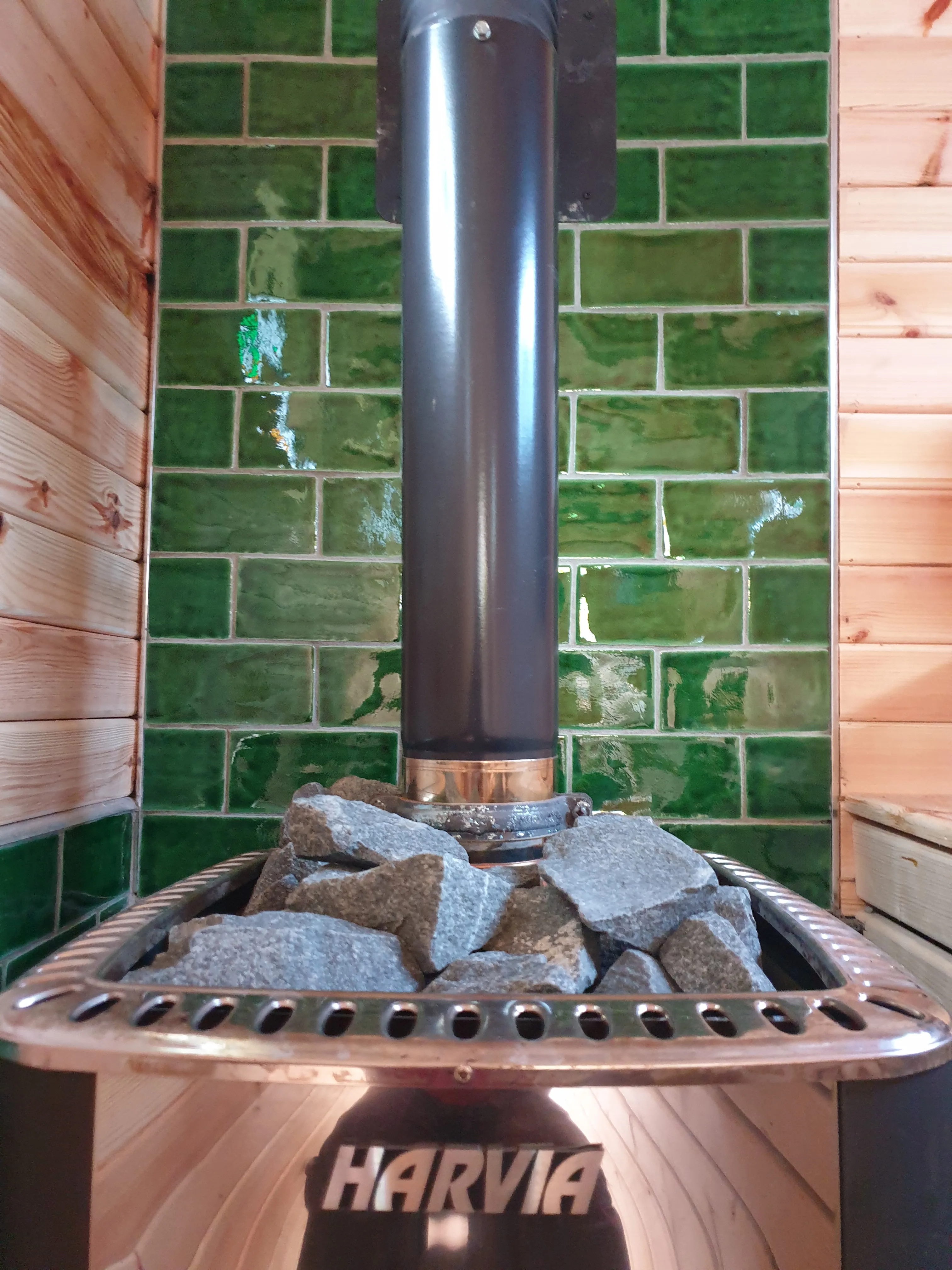 Bottle-green glazed tiles behind the wood-burning stove
